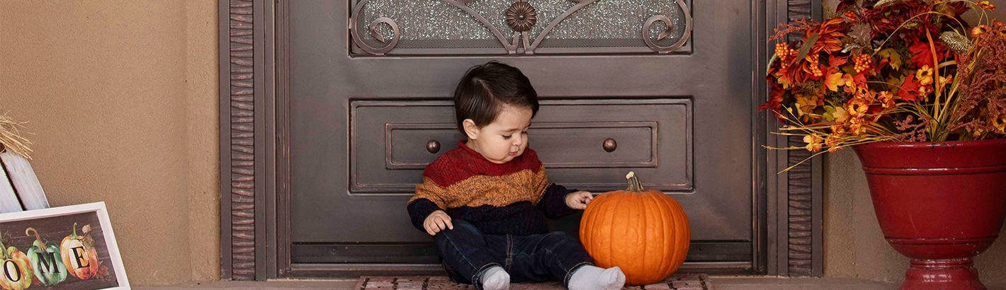 image of baby sitting by front door of house