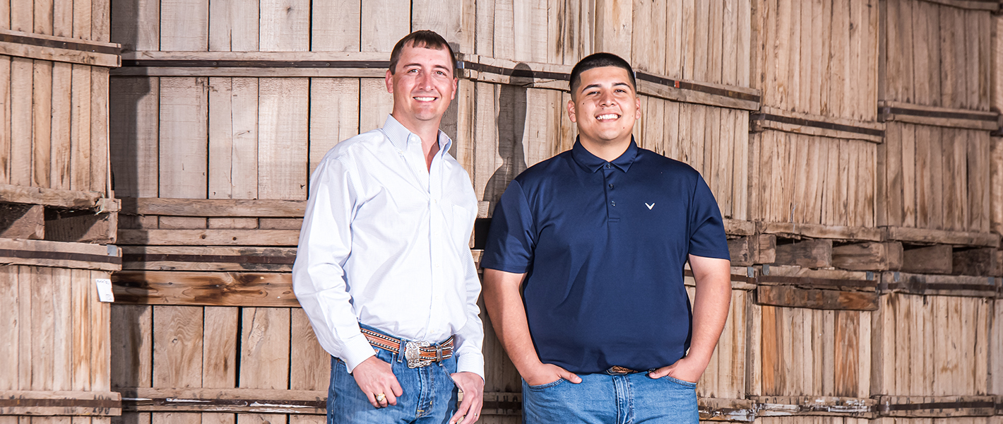 two men smiling standing in a barn