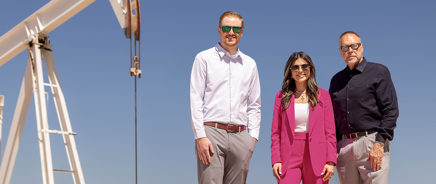 Three bankers standing in front of a pumpjack