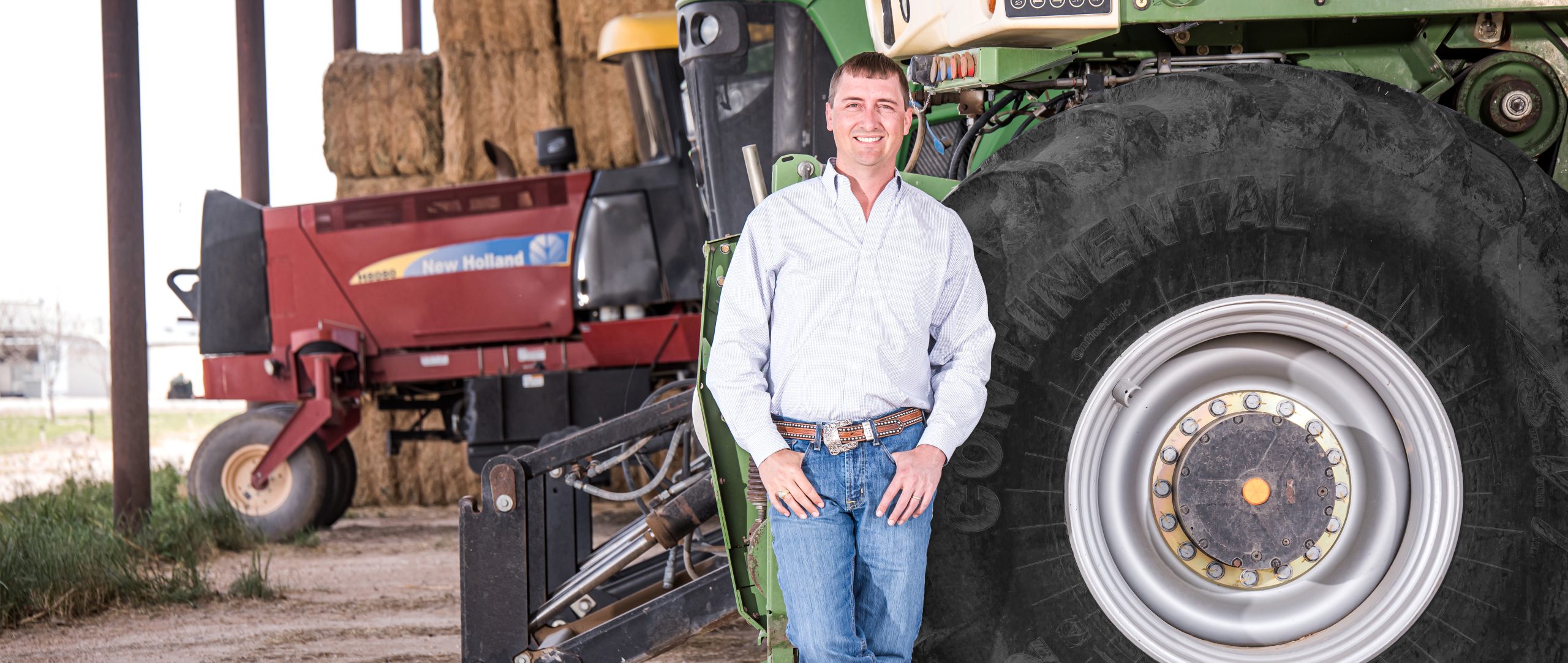 man smiling and standing in front of farming tractor